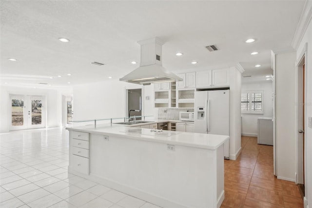 kitchen featuring island range hood, white appliances, visible vents, white cabinetry, and light countertops