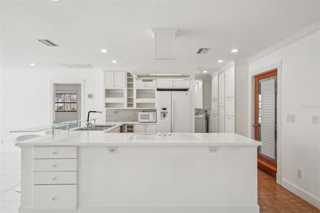 kitchen featuring white appliances, washer / clothes dryer, light countertops, and a sink