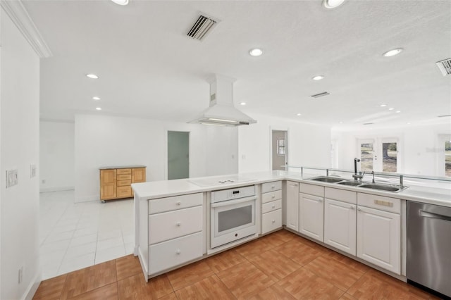 kitchen with light countertops, visible vents, white cabinetry, island range hood, and white appliances