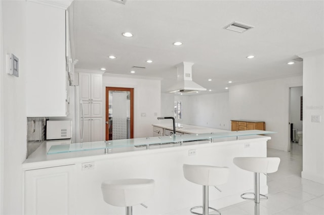 kitchen with a peninsula, white cabinetry, a breakfast bar area, and light countertops