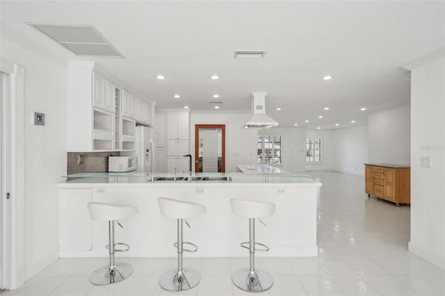 kitchen with light countertops, glass insert cabinets, white cabinets, ventilation hood, and a peninsula