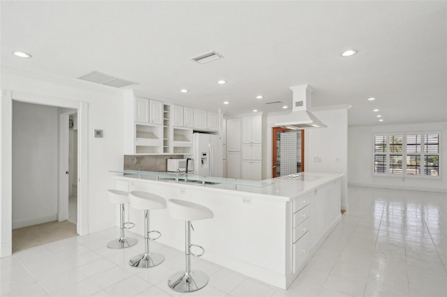 kitchen with white refrigerator with ice dispenser, open shelves, visible vents, white cabinetry, and a peninsula