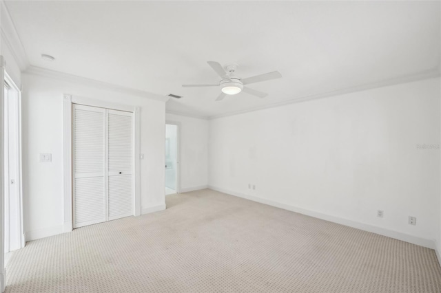 unfurnished bedroom featuring light carpet, baseboards, visible vents, ornamental molding, and a closet