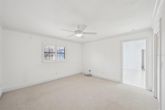 spare room featuring baseboards, ornamental molding, a ceiling fan, and light colored carpet