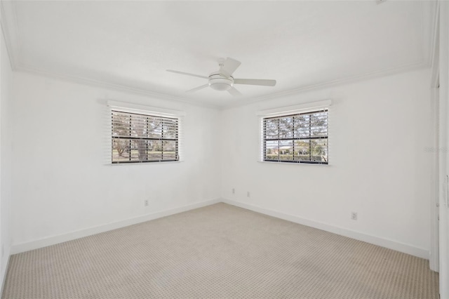 empty room featuring light colored carpet, crown molding, baseboards, and ceiling fan