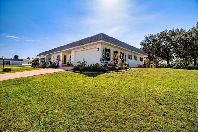 view of front of home with mansard roof, an attached garage, a shingled roof, decorative driveway, and a front yard