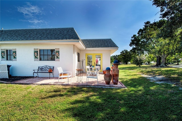 back of house with mansard roof, roof with shingles, a patio area, and a lawn