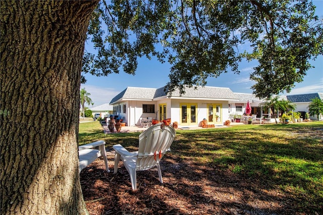 back of house featuring a shingled roof, french doors, and a lawn