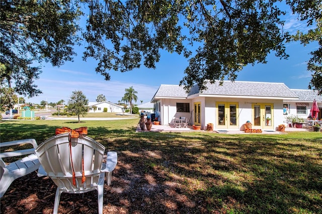 rear view of house with a yard, french doors, roof with shingles, and a patio area