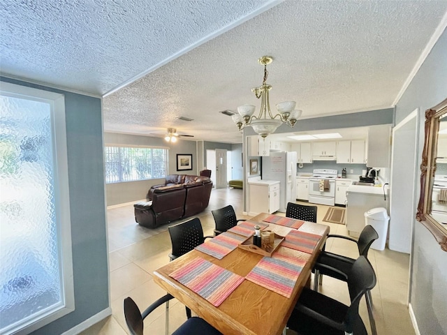 tiled dining space featuring sink, a textured ceiling, and ceiling fan with notable chandelier