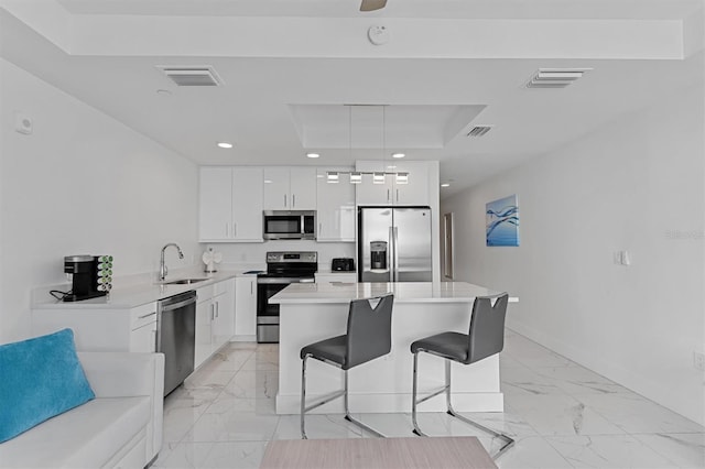 kitchen featuring decorative light fixtures, light tile flooring, a kitchen island, stainless steel appliances, and sink