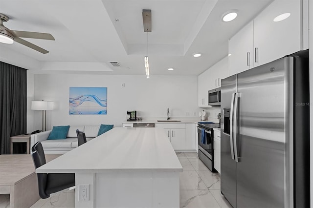 kitchen featuring stainless steel appliances, a tray ceiling, white cabinets, ceiling fan, and light tile floors