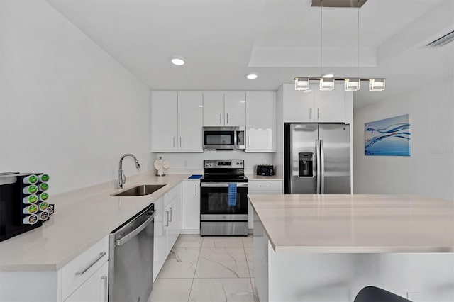 kitchen with stainless steel appliances, decorative light fixtures, light tile floors, sink, and white cabinetry