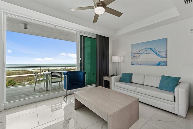 living room featuring ceiling fan, a healthy amount of sunlight, a water view, and light tile floors