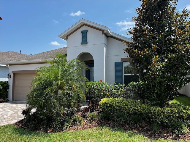 view of front of property with a garage, roof with shingles, decorative driveway, and stucco siding