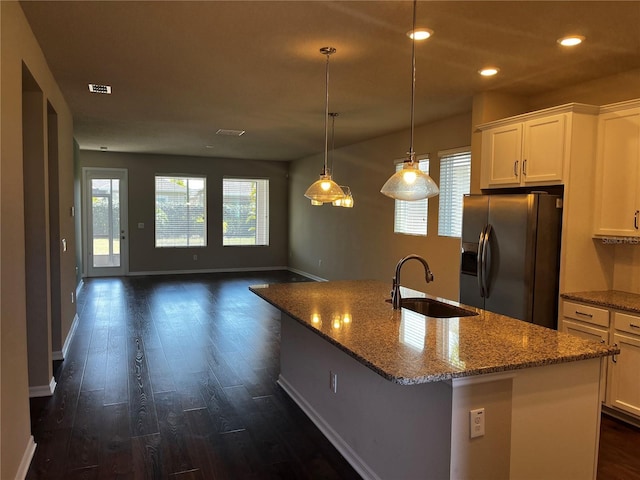 kitchen featuring dark wood-style floors, stainless steel refrigerator with ice dispenser, recessed lighting, a sink, and light stone countertops