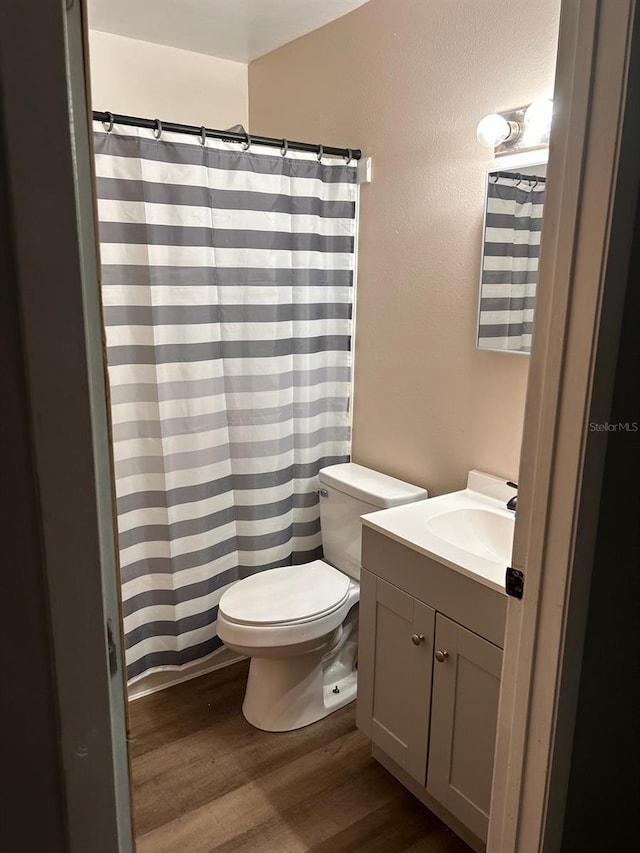 bathroom with toilet, hardwood / wood-style flooring, and vanity