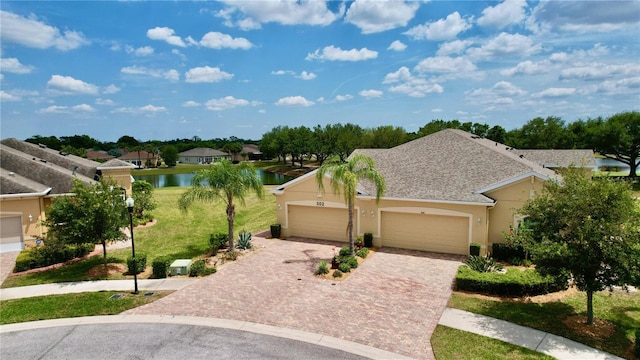 ranch-style house with a garage, a front lawn, and a water view