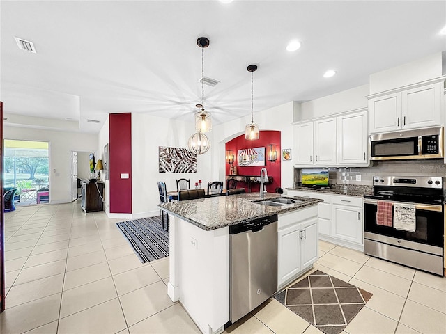 kitchen with stainless steel appliances, sink, an island with sink, and white cabinets