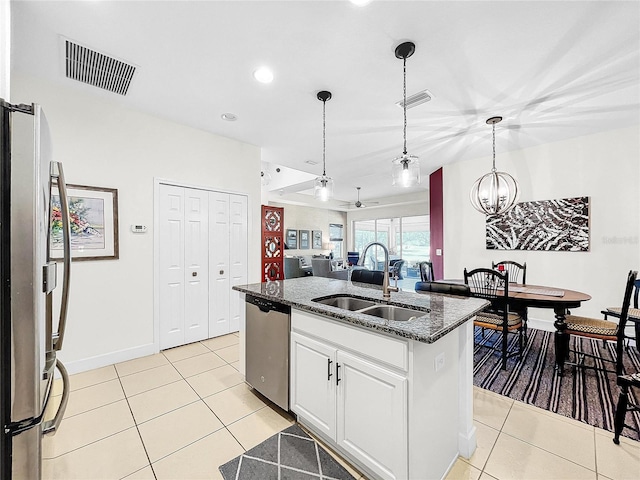 kitchen with stainless steel appliances, white cabinets, decorative light fixtures, sink, and light tile floors