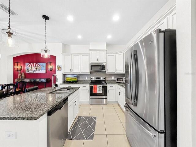 kitchen featuring stainless steel appliances, white cabinets, light tile flooring, and pendant lighting