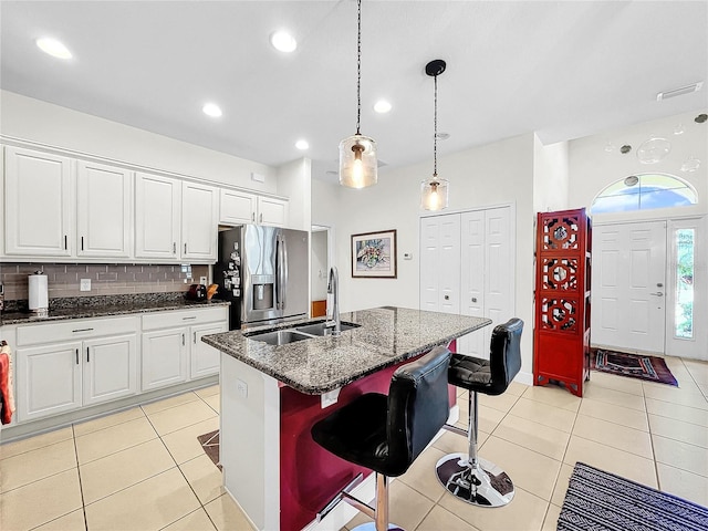 kitchen featuring a center island with sink, white cabinets, and tasteful backsplash