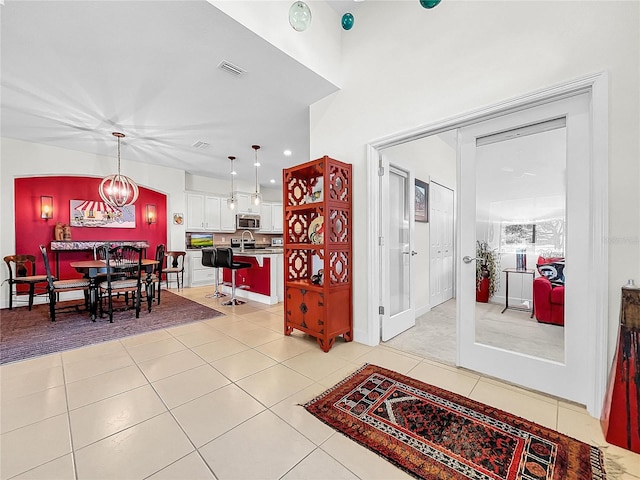 interior space with pendant lighting, an inviting chandelier, light tile floors, white cabinetry, and appliances with stainless steel finishes