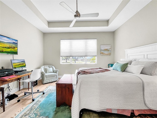 bedroom featuring wood-type flooring, ceiling fan, and a raised ceiling