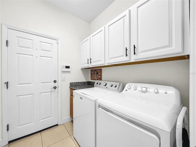 laundry area featuring washer and dryer, cabinets, and light tile floors