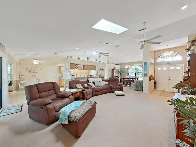 living room featuring a skylight, ceiling fan with notable chandelier, and light carpet