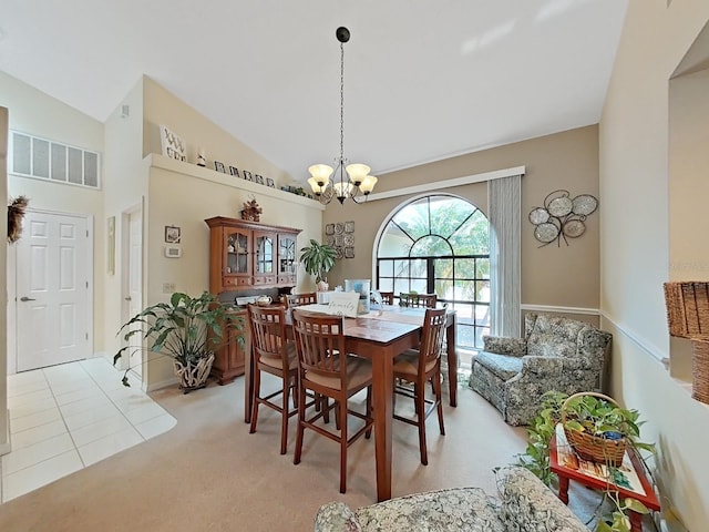 carpeted dining space featuring a notable chandelier and high vaulted ceiling