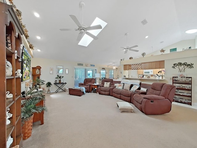 carpeted living room with ceiling fan and vaulted ceiling with skylight