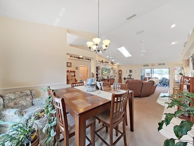 dining room with light carpet, high vaulted ceiling, a skylight, and ceiling fan with notable chandelier