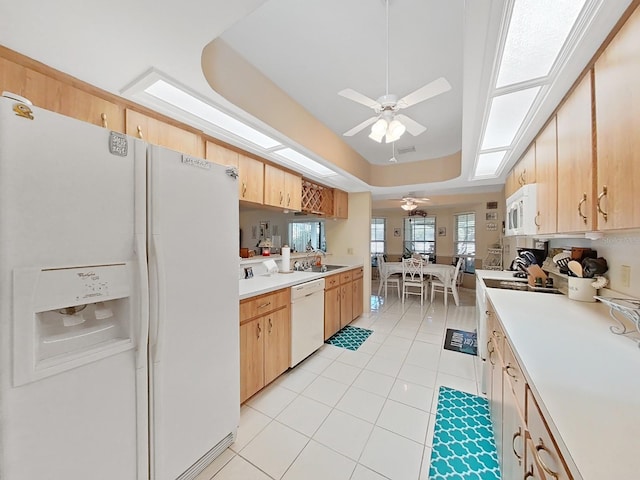 kitchen with light brown cabinets, ceiling fan, white appliances, light tile flooring, and a raised ceiling