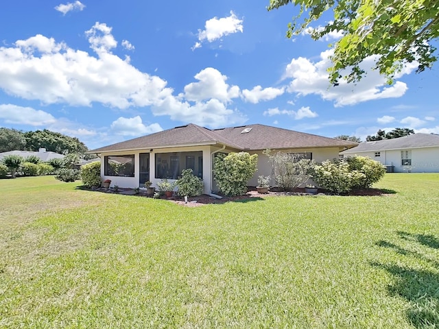 back of property featuring a sunroom and a lawn