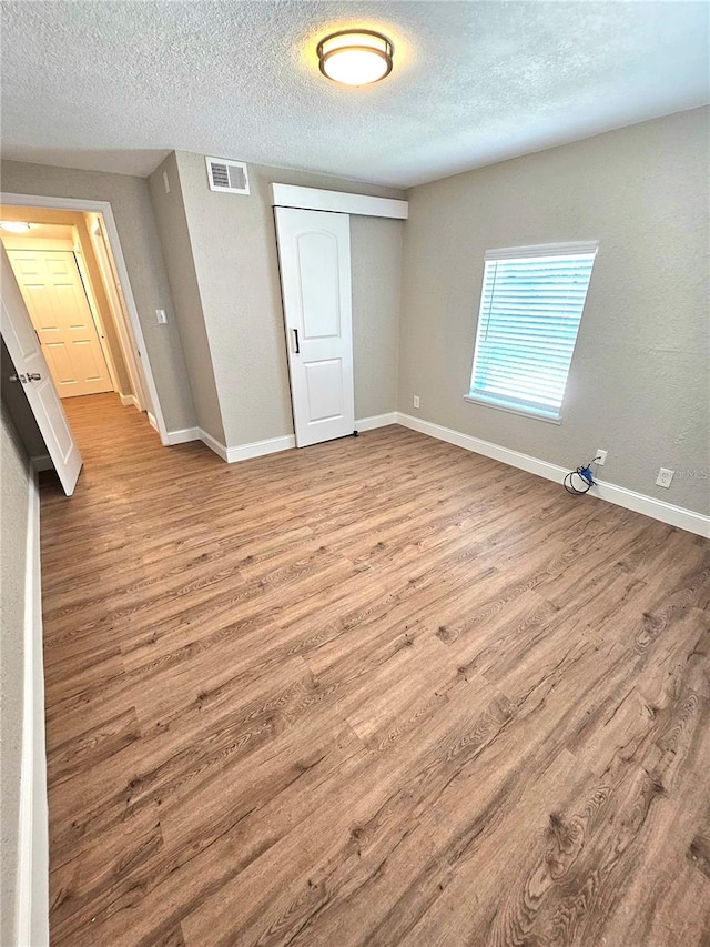 unfurnished bedroom featuring a textured ceiling, a closet, and hardwood / wood-style floors