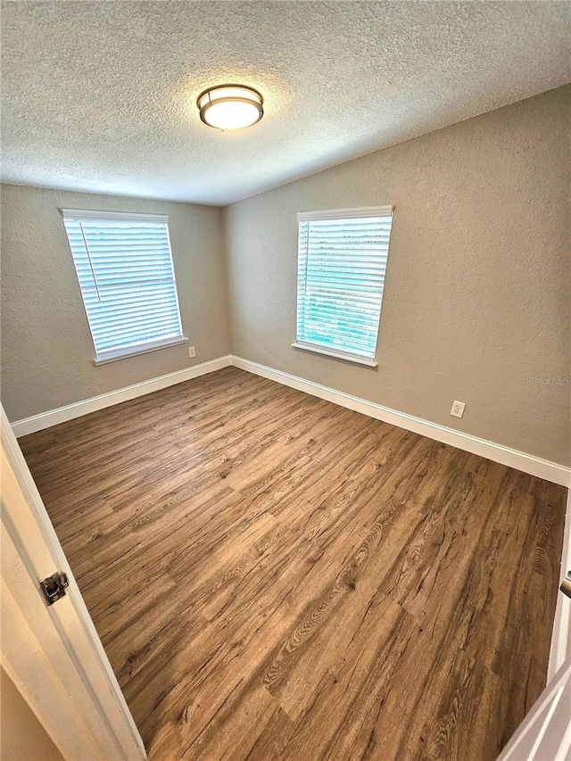 spare room featuring hardwood / wood-style flooring and a textured ceiling