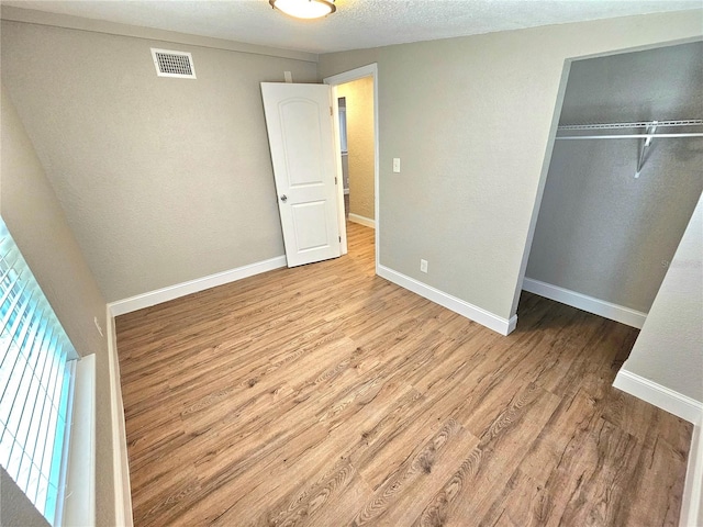 unfurnished bedroom with a textured ceiling, a closet, and hardwood / wood-style floors