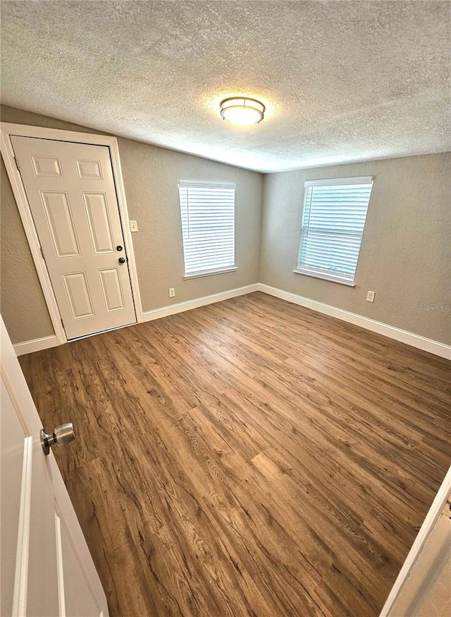 unfurnished room featuring a textured ceiling and dark hardwood / wood-style floors