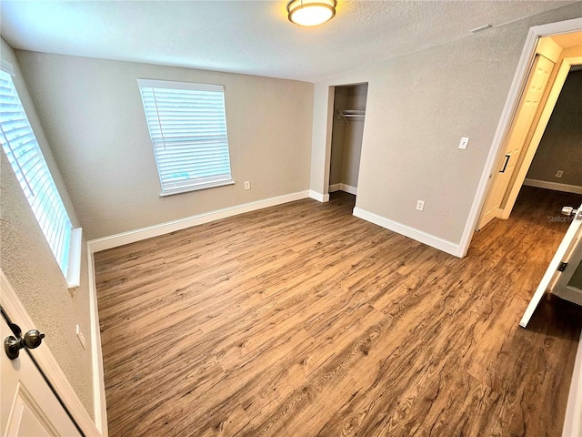 unfurnished bedroom with a closet, multiple windows, and hardwood / wood-style floors