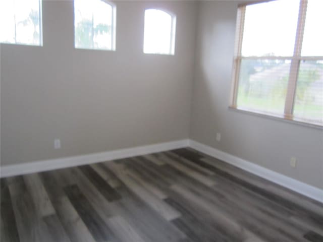 unfurnished room featuring a healthy amount of sunlight and dark hardwood / wood-style floors