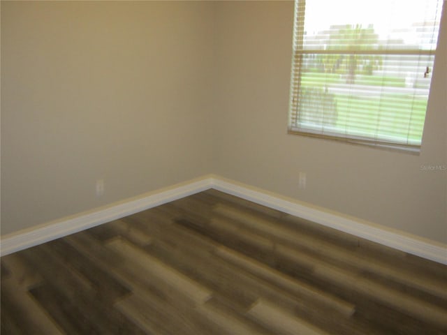 empty room featuring a wealth of natural light and dark wood-type flooring