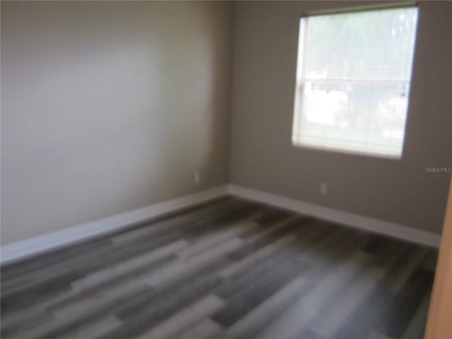 unfurnished room with plenty of natural light and dark hardwood / wood-style flooring