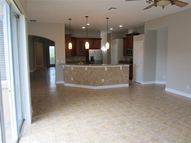 kitchen featuring stainless steel fridge with ice dispenser, built in microwave, decorative light fixtures, ceiling fan, and light tile floors