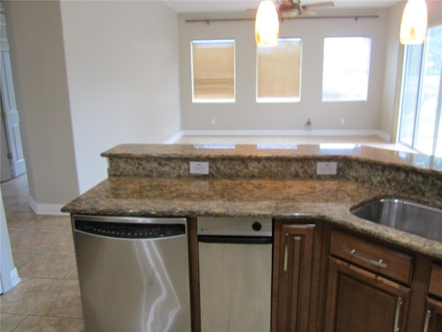 kitchen with dark stone counters, dishwasher, dishwashing machine, light tile floors, and hanging light fixtures