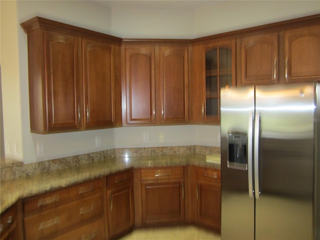 kitchen featuring stainless steel fridge and stone countertops