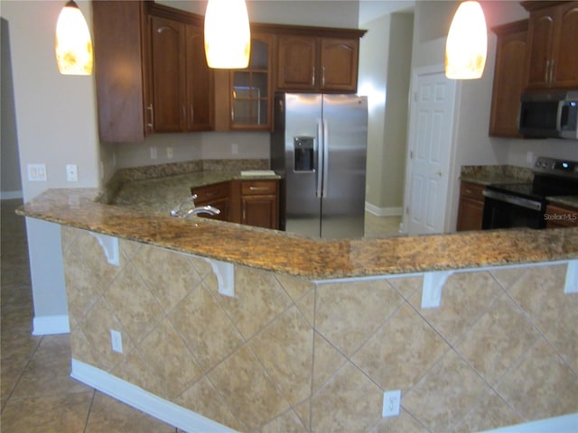 kitchen featuring stainless steel appliances, stone countertops, tile floors, a kitchen bar, and pendant lighting