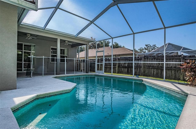 view of pool with glass enclosure, a patio area, and ceiling fan