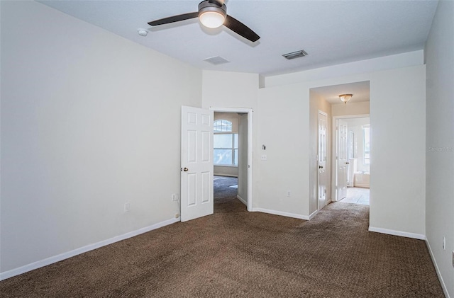 empty room with ceiling fan and dark colored carpet