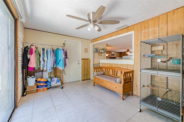 tiled bedroom with wooden walls, a closet, ceiling fan, and a textured ceiling